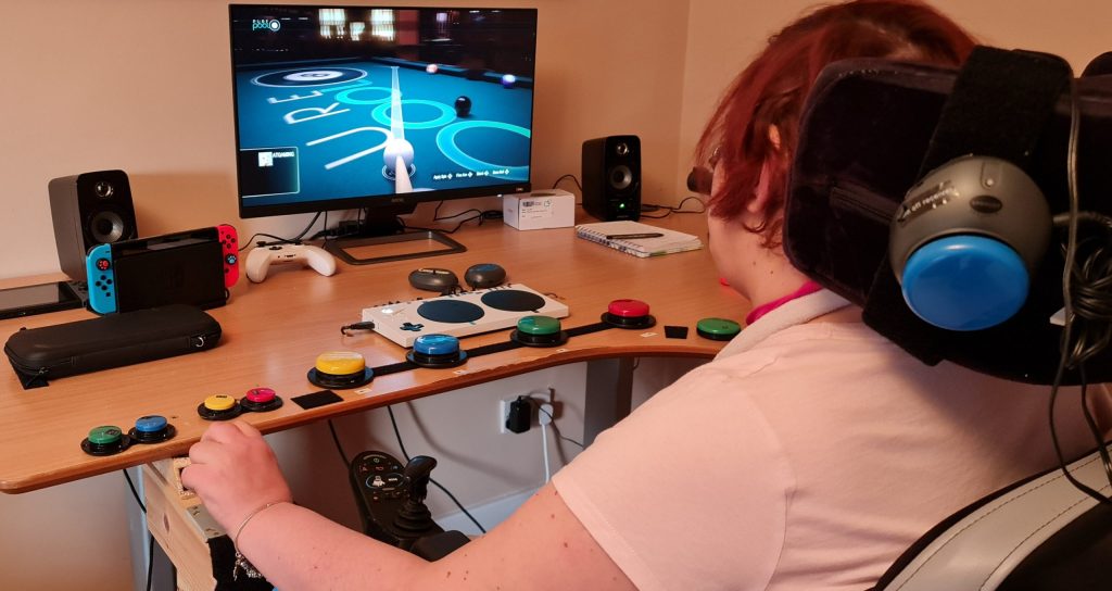 Person using a bespoke buttons and controller setup to play Pool on a screen